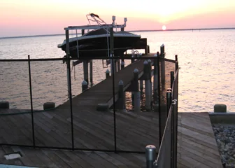Black mesh safety fence installed along a waterfront dock at sunset