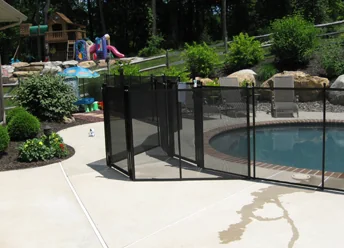 Black mesh safety fence around a raised spa beside a backyard play area