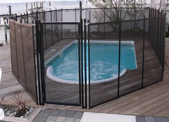 Black mesh pool fence with self-closing gate on a paver pool deck