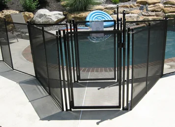 Black mesh pool fence with a self-closing, self-latching gate beside a landscaped pool