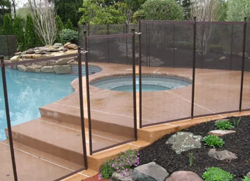 Brown mesh pool fence following the steps of a raised pool deck