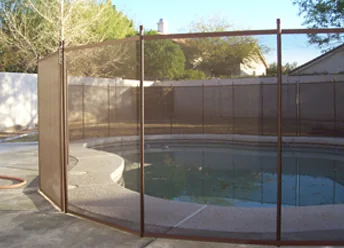 Brown mesh pool fence with brown poles around a backyard pool