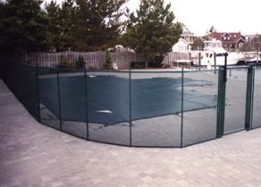 Green mesh pool fence around a covered pool on a paver deck